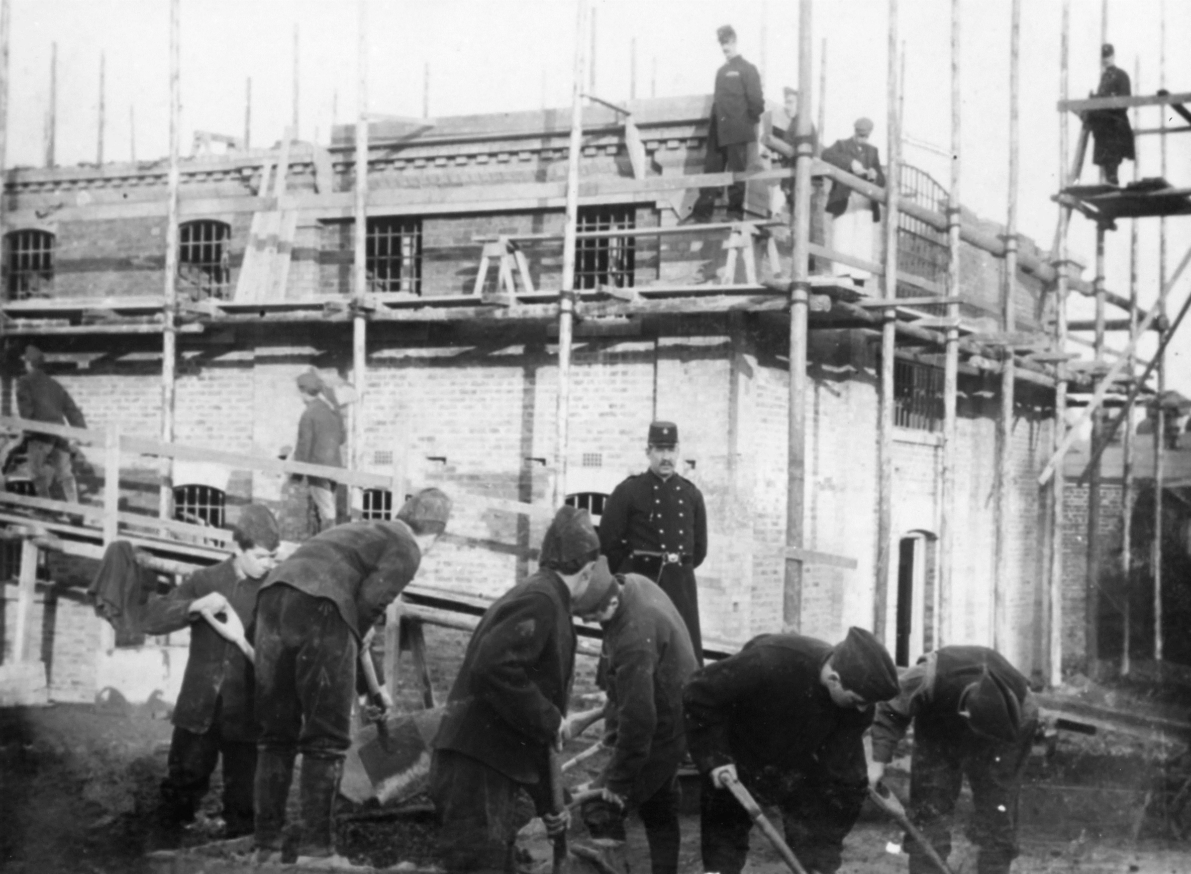 A black-and-white photograph of young men in uniform doing supervised work at a borstal.